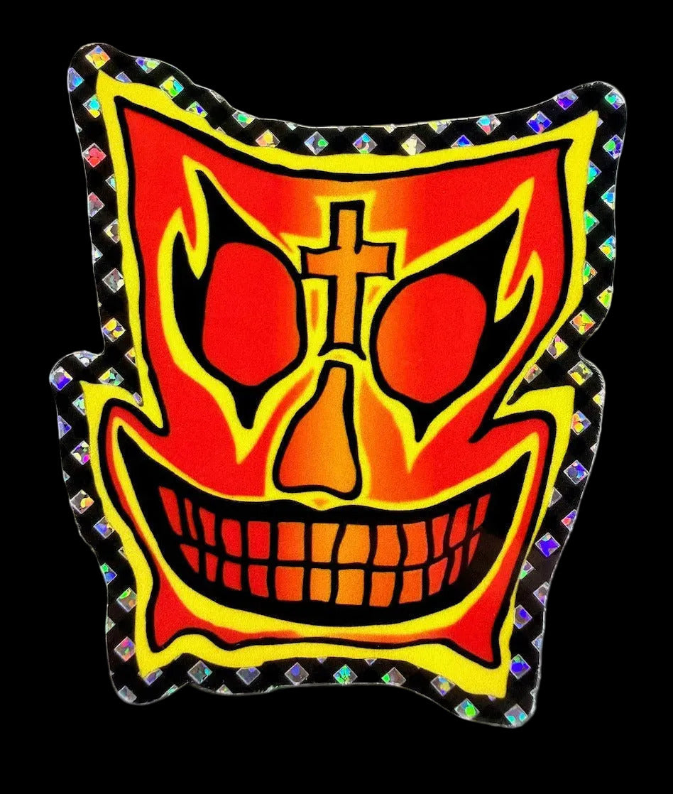 A die-cut John Grigley Pro Model Skateboard sticker featuring a stylized, fiery red and orange skull face with black outlines, a gold cross on the forehead, and a holographic diamond-patterned border, shown on a neutral gray background.