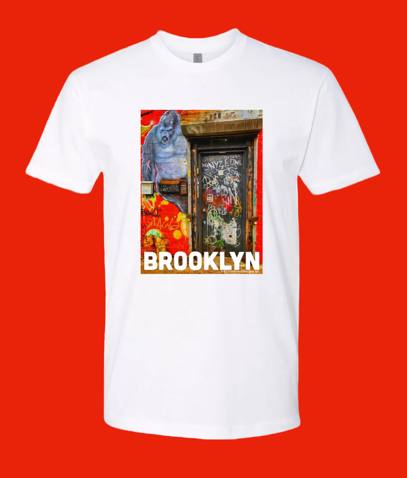 A white short-sleeve crewneck t-shirt featuring a colorful graphic print of a Brooklyn street scene with a blue gorilla and the word 'BROOKLYN' in bold white letters.