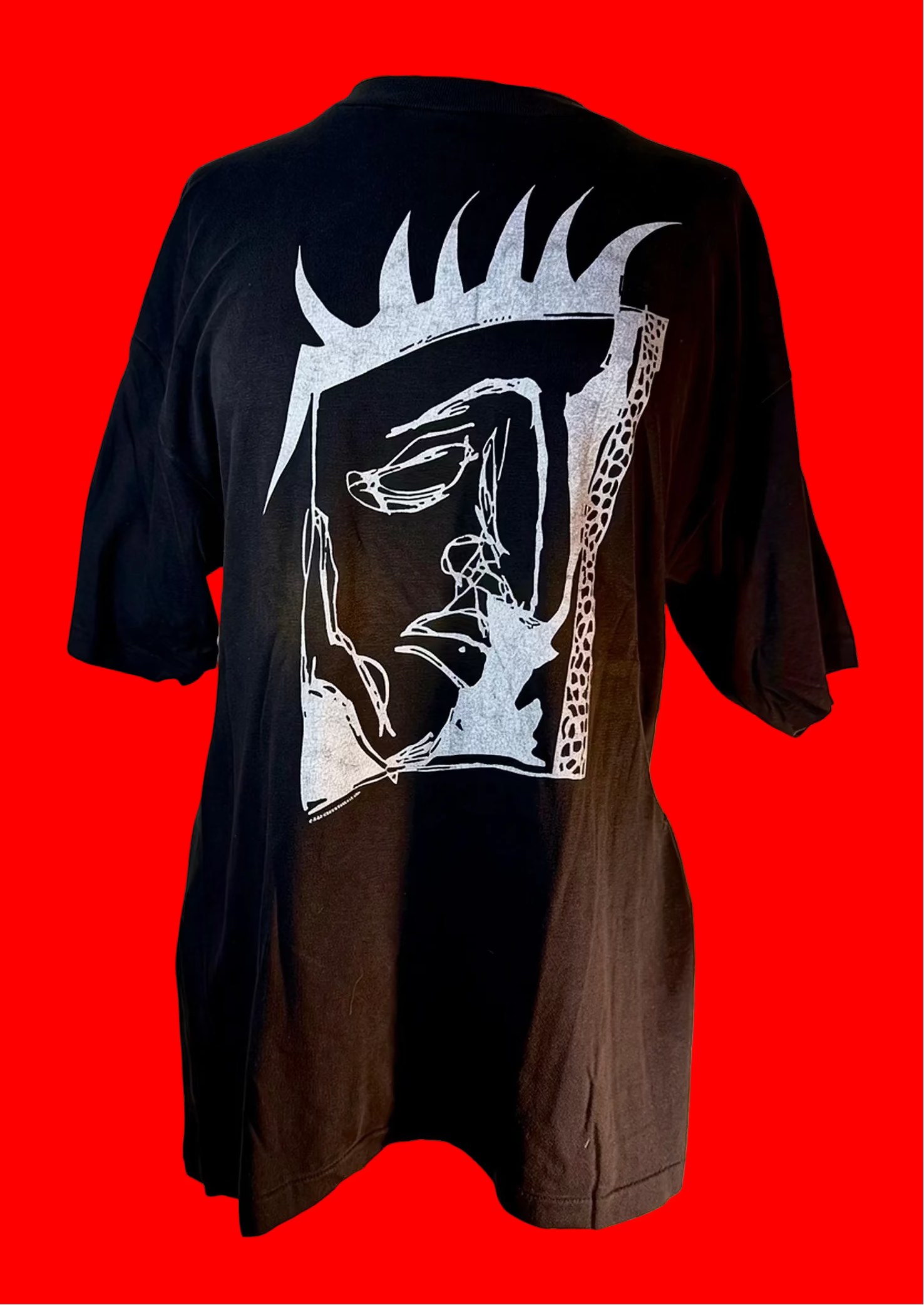 Black tee shirt with an artistic drawing of a kings face n white ink. The background is red.