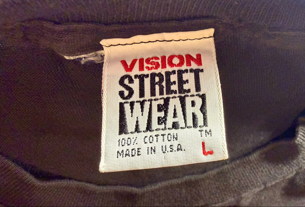 Close-up of a sewn-in clothing label reading 'VISION STREET WEAR' with '100% COTTON MADE IN U.S.