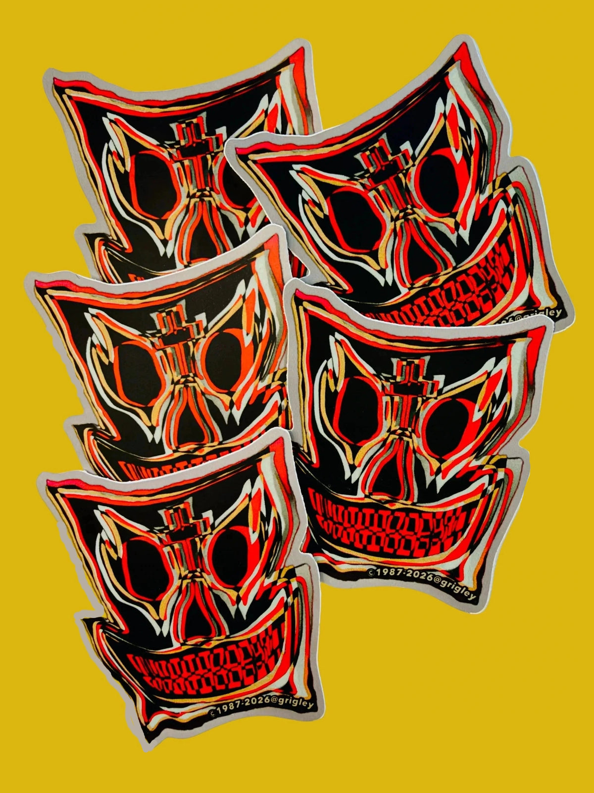Six identical die-cut stickers featuring a stylized red, black, and white John A. Grigley Pro Skate mask/skull design with gold outlines, arranged on a plain white background.