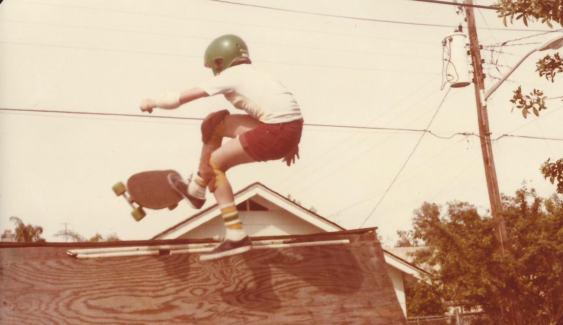Person skateboarding off a ramp with a helmet on, vintage photo style.