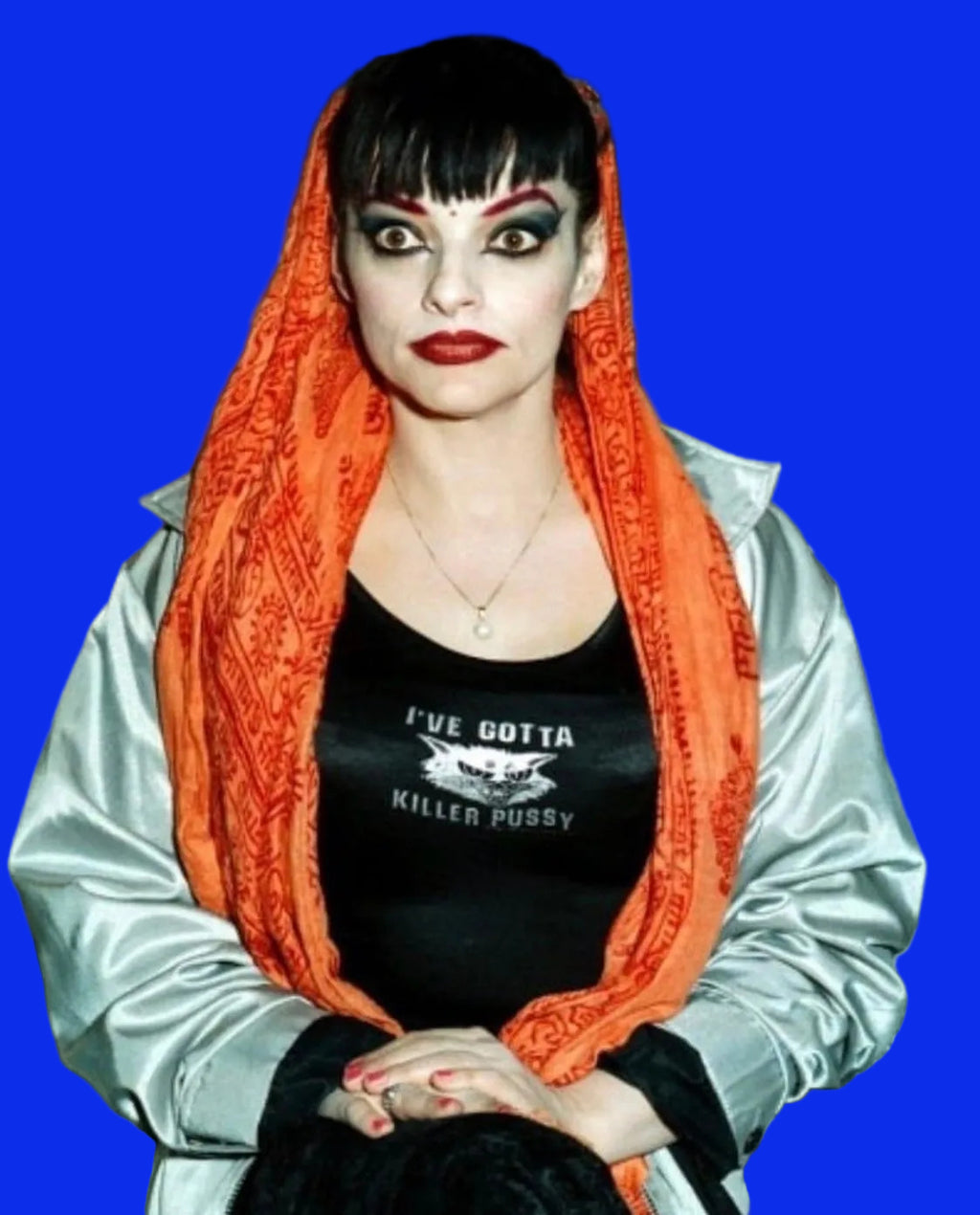 Person wearing an orange scarf and black shirt with text in a room with shelves in the background
