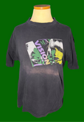 A faded black graphic t-shirt displayed on a mannequin torso on a green background. The shirt features a large, colorful front graphic with the word 'VISION' and a stylized illustration in green, yellow, and white.