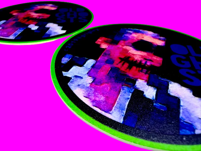 Two round coasters with colorful abstract designs on a white surface